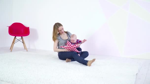 Молодая мать играет со своим 6-месячным сыном на ковре — стоковое видео