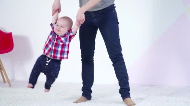 Jovem mãe balançando seu pequeno filho bebê em suas mãos câmera lenta — Vídeo de Stock