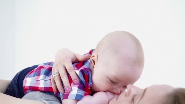 Jonge moeder opleggen van het tapijt met haar babyjongen op haar borst te leggen — Stockvideo