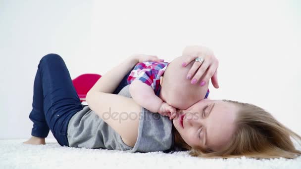 Genç anne bebek oğlu onun göğüs ağır çekim portre üzerinde döşeme ile halı üzerinde döşeme — Stok video
