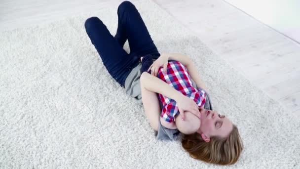 Young mother laying on the carpet with her baby boy laying on her chest slow motion — Stock Video