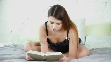 Lotus poz yatakta oturan ve bir kitap closeup okuma güzel kadın