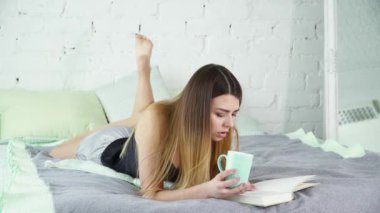 Genç esmer kadın onun yatağında bir kitap okuma