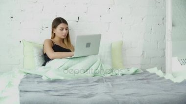 Genç kadın yatakta onu laptop kullanma
