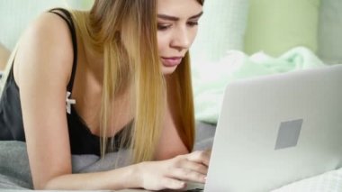 Bir yatakta döşeme ve onu laptop yazarak güzel kadın
