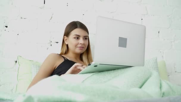 Jovem mulher bonita usando seu laptop na cama — Vídeo de Stock