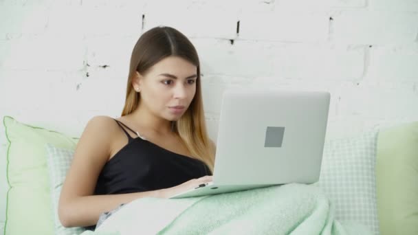 Mujer joven usando su portátil en la cama primer plano — Vídeo de stock