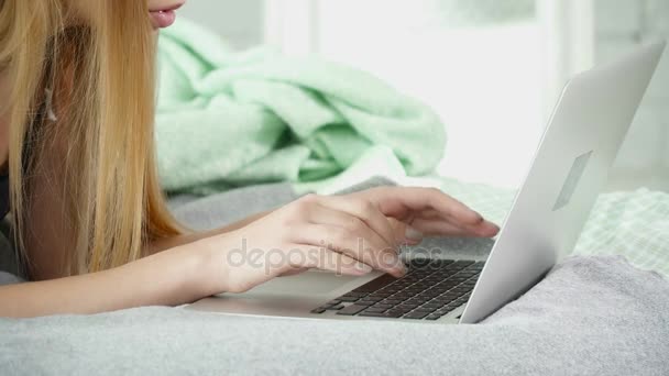 Joven morena acostada en una cama y usando su portátil de primer plano — Vídeo de stock