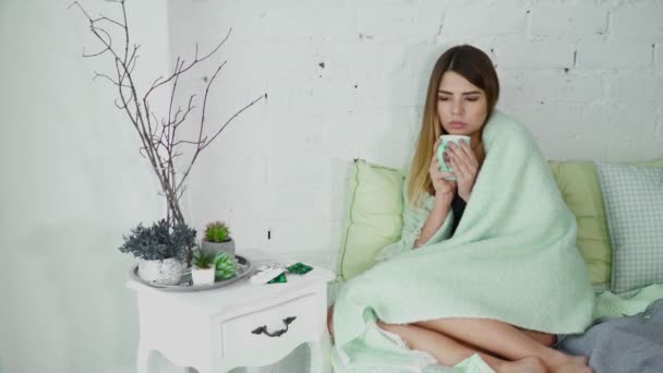 Нездоровая молодая женщина в постели под одеялом — стоковое видео