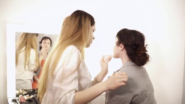 Makeupartist tillämpa bas på unga kvinnans ansikte — Stockvideo