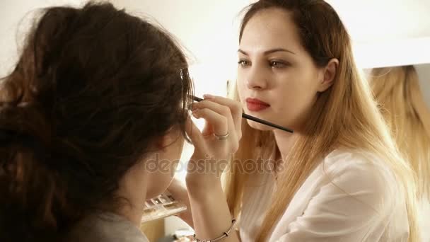 Maquiagem artista criando a maquiagem para uma mulher — Vídeo de Stock