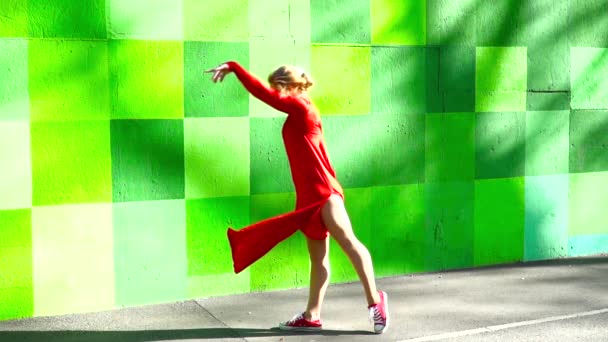 Young woman in a red dress dancing on the colored background — Stock Video