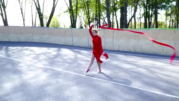 Mladá žena v červených šatech tančí s pásem karet na hřišti — Stock video