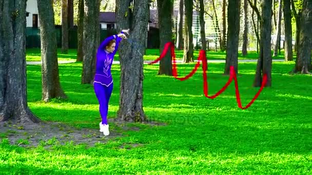 Joven gimnasta bailando con la cinta en el parque — Vídeos de Stock