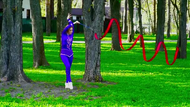 Joven gimnasta bailando con la cinta en el parque en cámara lenta — Vídeo de stock