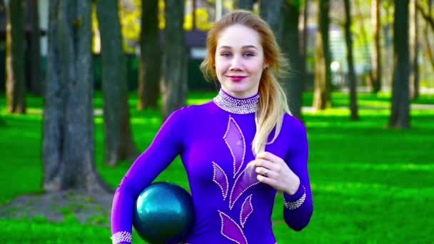 Retrato de una joven gimnasta con la pelota sonriendo a la cámara en el parque cámara lenta — Vídeos de Stock