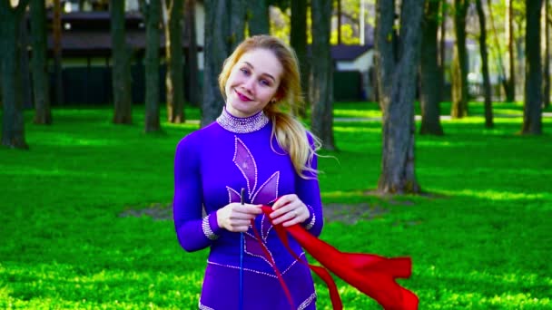 Portrait d'une jeune gymnaste avec le ruban souriant à la caméra dans le parc au ralenti — Video