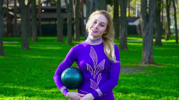 Retrato de una joven gimnasta con pelota sonriendo a la cámara en el parque cámara lenta — Vídeos de Stock