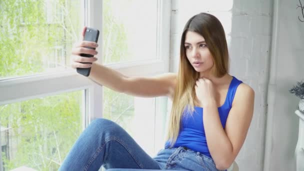 Hermosa joven mujer haciendo selfie en la ventana alféizar primer plano — Vídeos de Stock