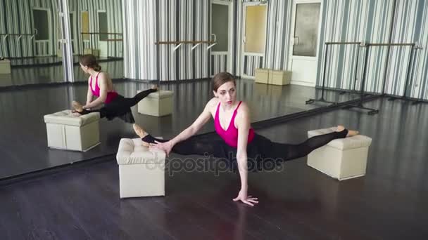 Junge Frau streckt sich im Tanzstudio vor dem Spiegel — Stockvideo