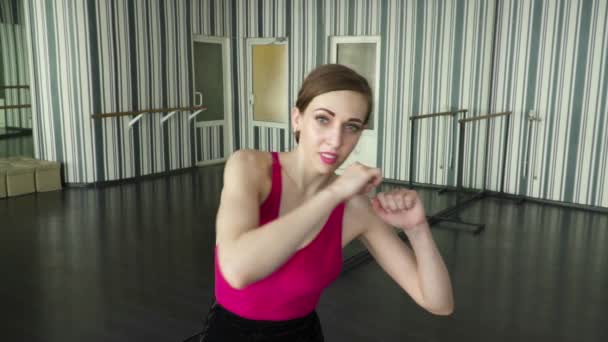 Молода жінка танцює, показуючи удар до камери — стокове відео