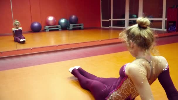 Fiatal nő tornász nő bemelegedési a padlón — Stock videók