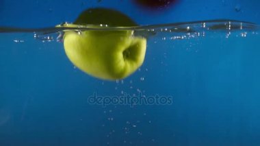 Mavi backgrond ağır çekim üzerinde düşen suya yeşil taze elma closeup