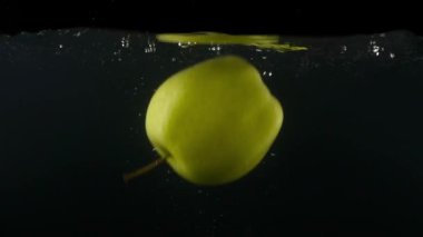Yeşil elma siyah backgrond ağır çekim üzerinde düşen suya closeup