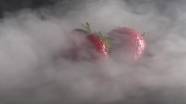 Morangos frescos orgânicos em fumaça no fundo preto câmera lenta — Vídeo de Stock