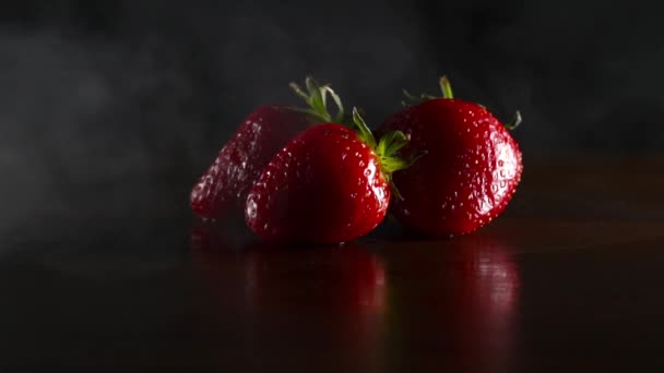 Biologische verse lekkere aardbeien in rook op de zwarte achtergrond — Stockvideo