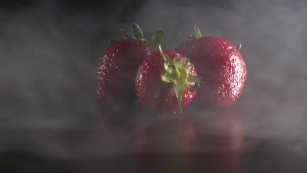 Органическая свежая вкусная клубника в дыму на черном фоне замедленной съемки — стоковое видео