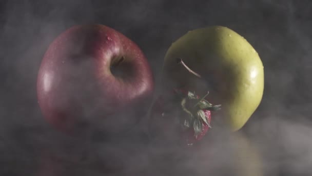 Органічні свіжі смачні яблука і полуниця в диму на чорному тлі — стокове відео