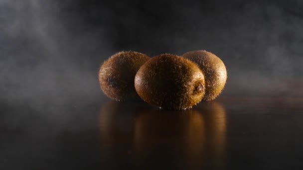 Organic fresh kiwi in smoke on the black background slow motion — Stock Video