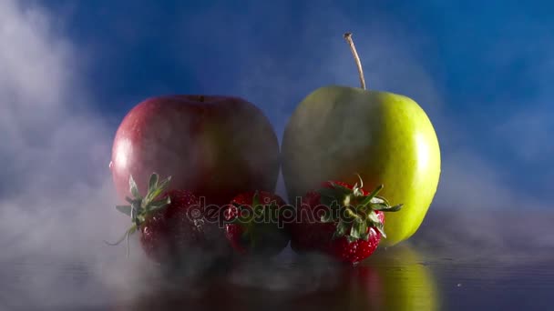 Органічні свіжі смачні фрукти в диму на синьому фоні — стокове відео