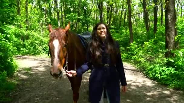 Mujer joven caminando con el caballo desde el bosque — Vídeo de stock