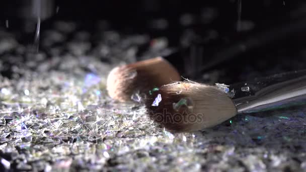 Glasperlen fallen auf Make-up-Pinsel auf schwarzem Hintergrund, abstrakte Zeitlupe — Stockvideo