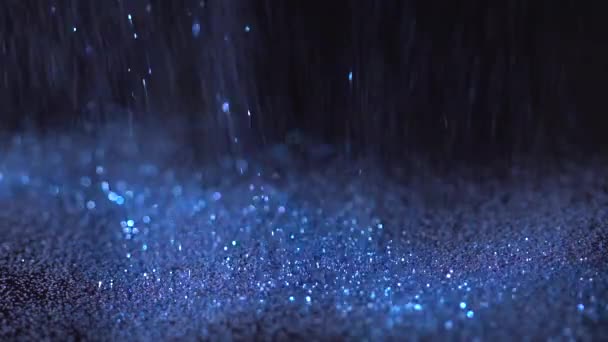 Brilhantes azuis caindo sobre o fundo preto, movimento lento abstrato — Vídeo de Stock