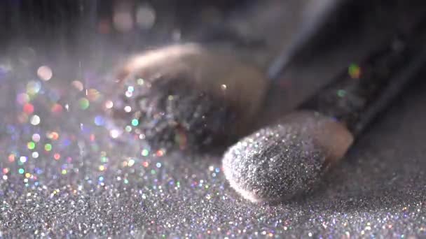 Paillettes blanches tombant sur des pinceaux de maquillage sur le fond noir, ralenti abstrait — Video