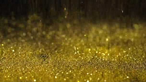 Gyllene gult glitter faller på den svarta bakgrunden, abstrakt slowmotion — Stockvideo