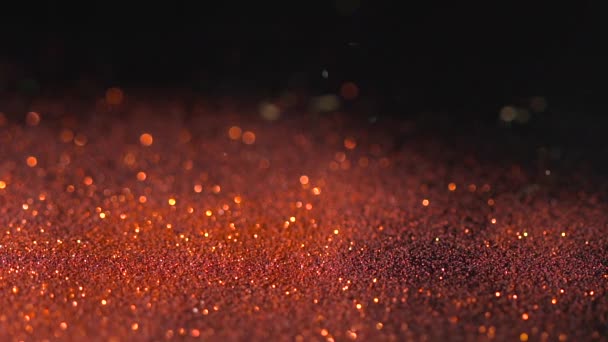 Golden orange shimmer falling on the black background, abstract slow motion — Stock Video