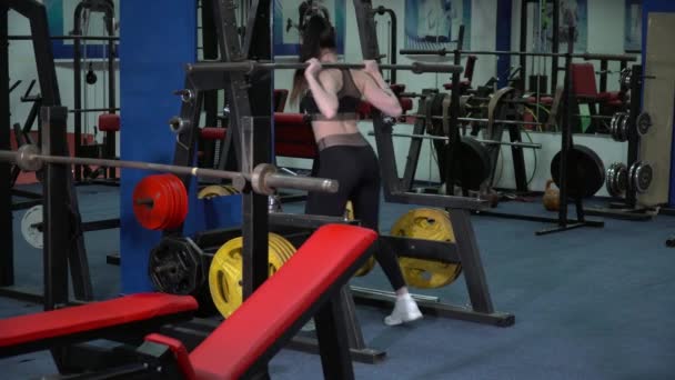 Молода жінка робить наполовину присідання в спортзалі — стокове відео