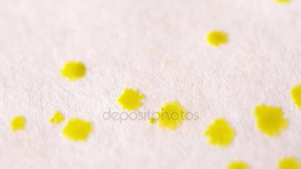 Närbild av gula droppar av Akvarell på papper slow motion — Stockvideo