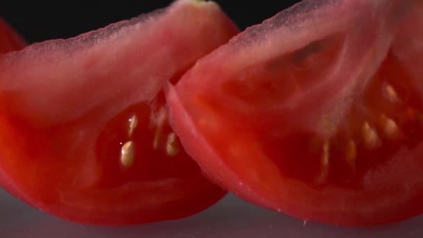 Крупный план нарезанных помидоров на черном фоне замедленной съемки — стоковое видео
