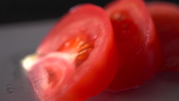 Свежие нарезанные помидоры на черном фоне замедленной съемки, макрос — стоковое видео