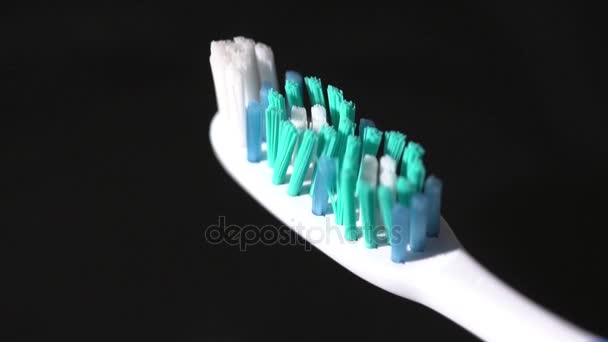 Closeup of toothbrush rotating on the black background slow motion — Stock Video