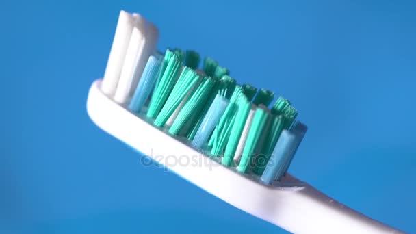 Primer plano del cepillo de dientes en el fondo azul cámara lenta — Vídeos de Stock