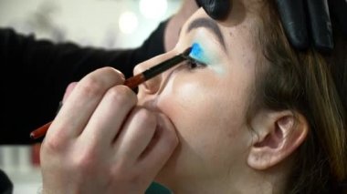 Adam makyaj sanatçısı mavi gölgeler closeup ile yüz sanat yapma