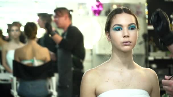 Truccatore rendendo il viso arte con ombre blu per una giovane donna nello studio di bellezza — Video Stock