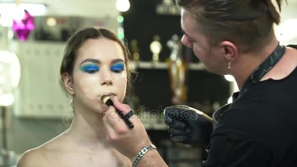 Maquillaje artista haciendo el arte de la cara para una mujer joven primer plano — Vídeo de stock