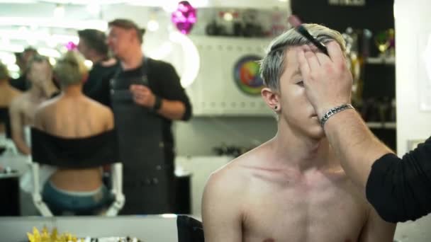 Make-up-Artist macht Gesicht-Art für einen blonden Mann vor dem Spiegel — Stockvideo